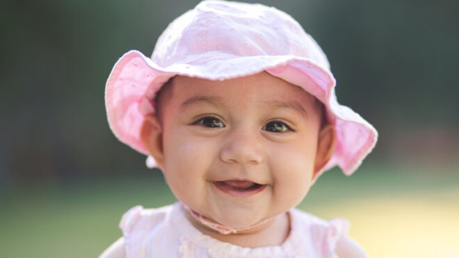 smiling baby girl dressed in a pink hat